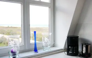 Fenster mit freiem Blick auf die Ostsee, Dünen und den Sandstrand in der Ferienwohnung in Warnemünde.