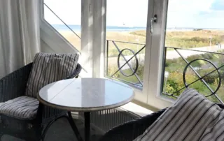 Zwei Stühle mit kleinem Tisch vor dem Fenster mit direktem Blick auf die Ostsee in der Villa am Strand