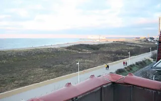 Promenade mit Blick auf Dünen, Strand, Wasser und weiten Himmel vor der Villa am Strand in Warnemünde.