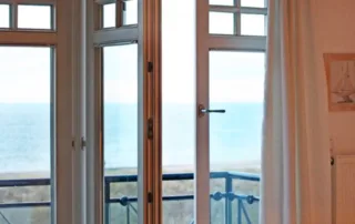 Blick durch Balkontür auf Strand, Ostsee und Wasser in Warnemünde nahe der Villa am Strand.