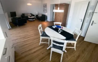 Offener Wohnbereich mit Küche, Esstisch, Sofa, Sessel und Fernseher in der Ferienwohnung an der Ostsee