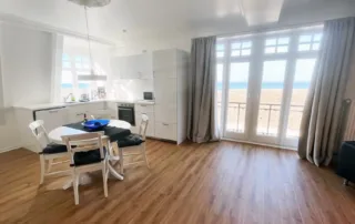 Küche mit Esstisch, Blick auf Balkonfenster und Ostseestrand in der Ferienwohnung in Warnemünde