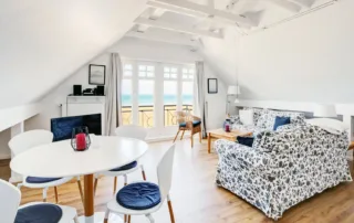 Heller Wohnbereich mit Sofa, Esstisch, vier Stühlen und Fenster in Ferienwohnung 2 in Warnemünde