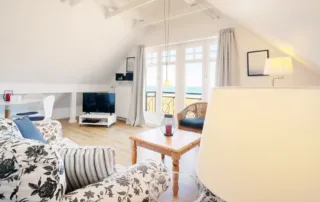 Heller Wohnbereich mit Sofa, Tisch, Esstisch und Fenster in der Ferienwohnung Villa am Strand