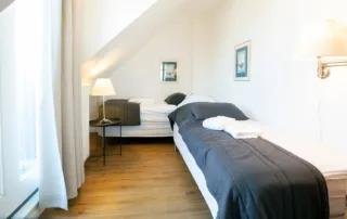 Helles Schlafzimmer mit zwei Einzelbetten und Balkontür in der Ferienwohnung an der Ostsee