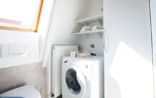 Badezimmer mit WC, Fenster, Ablagefläche und Waschmaschine in der Ferienwohnung an der Ostsee