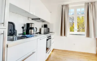 Weiße, voll ausgestattete Küche mit Fenster in der Ferienwohnung Villa am Strand in Warnemünde
